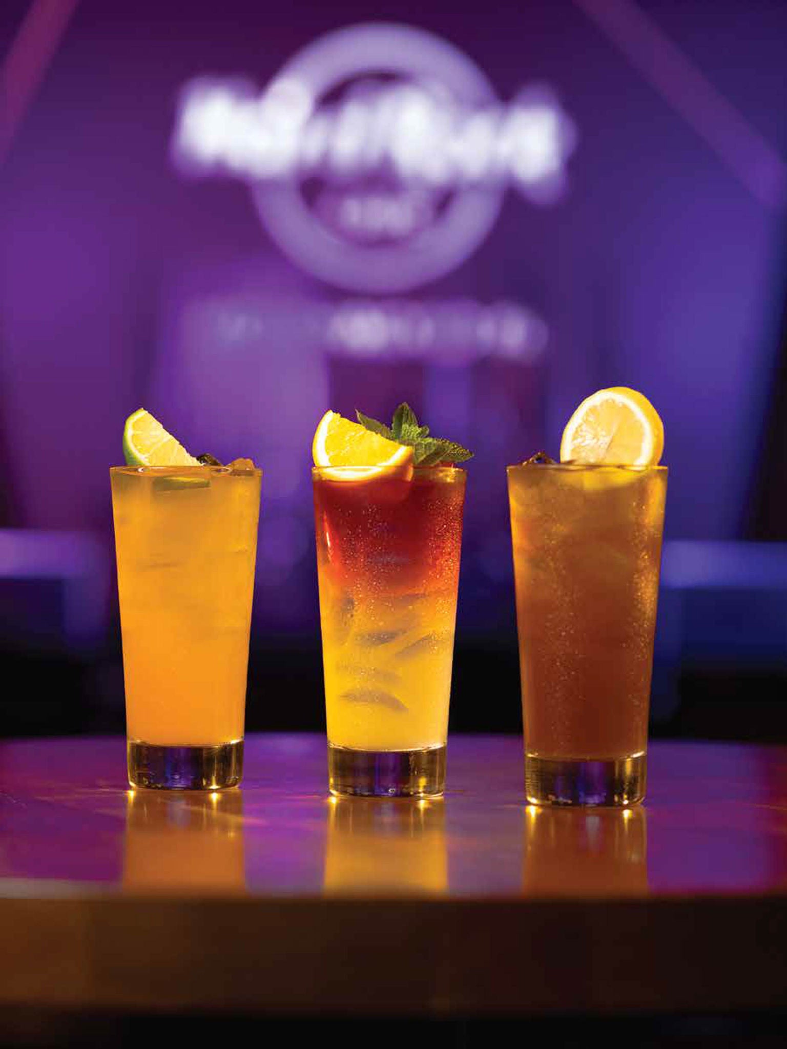 Three colorful cocktails on bar table with garnishes