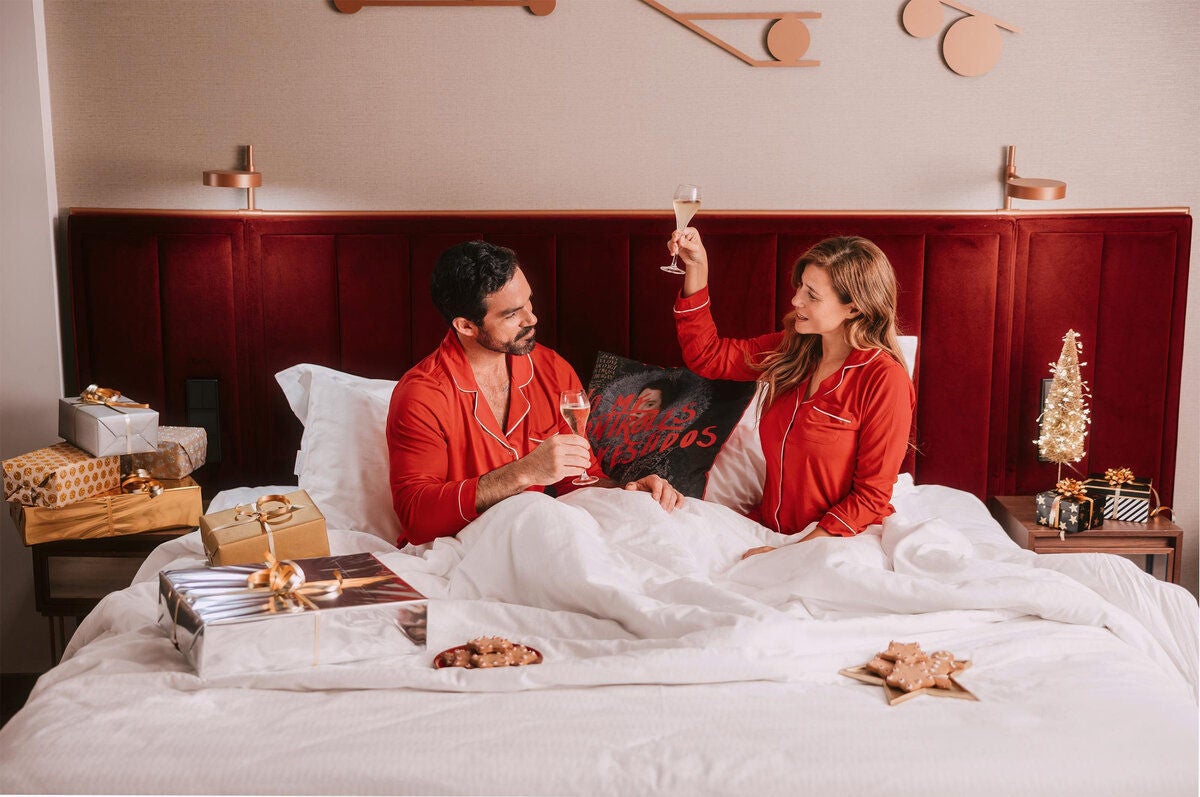 a man and woman in pajamas sitting on a bed with champagne